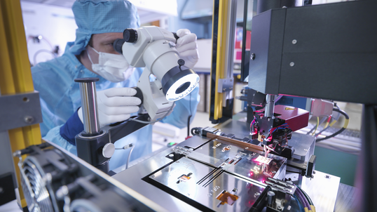High-tech manufacturer looking through microscope.